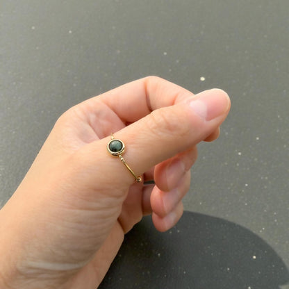 Hand wearing a green African Turquoise Gemstone Fidget Ring on a gray background