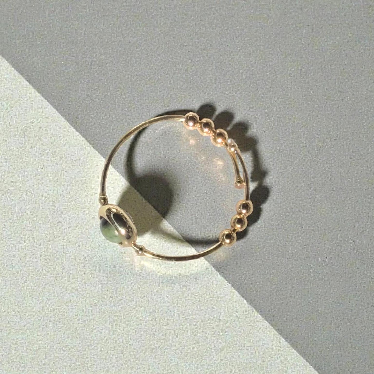 Top view of a Green African Turquoise Gemstone Fidget Ring on a two-tone gray and beige background