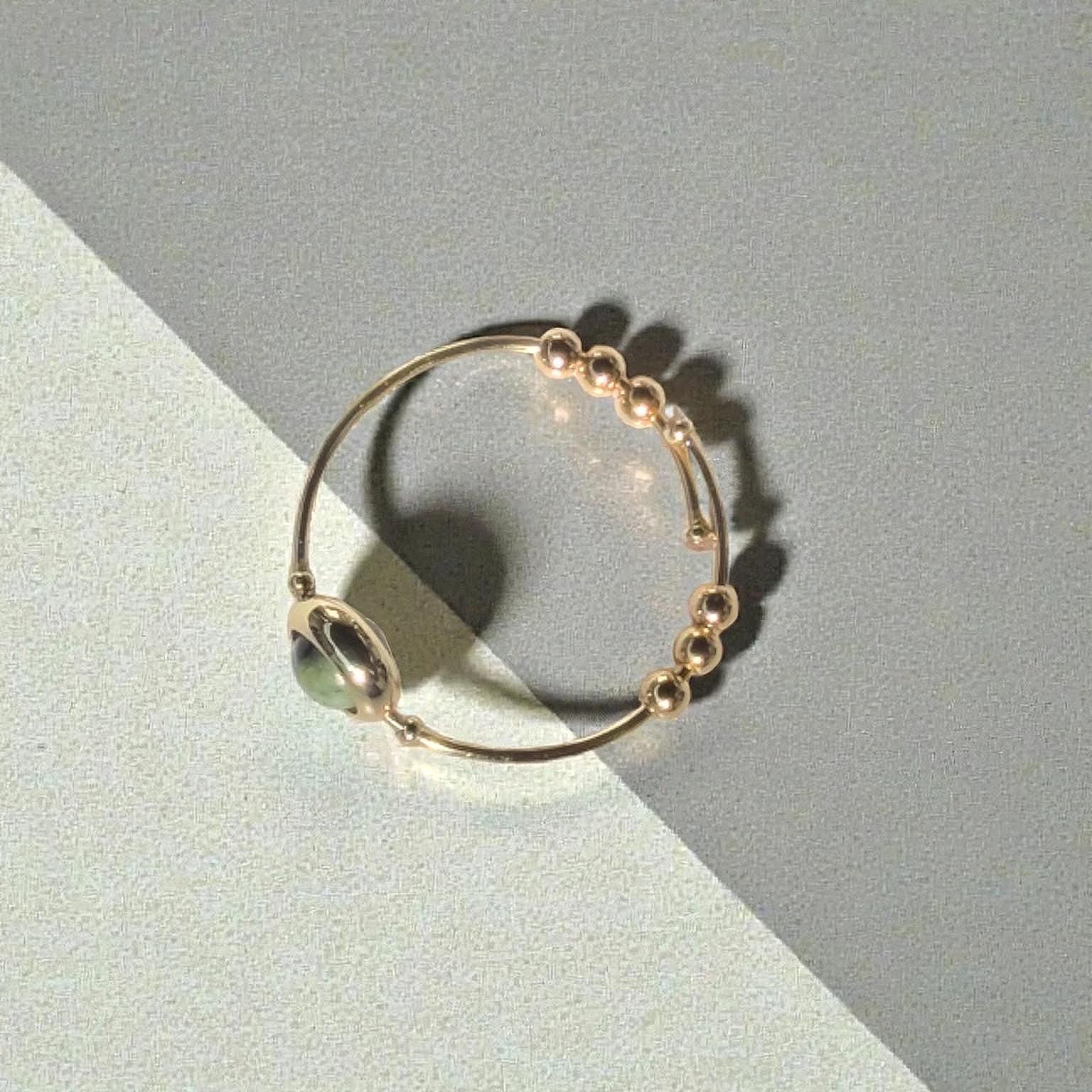 Top view of a Green African Turquoise Gemstone Fidget Ring on a two-tone gray and beige background