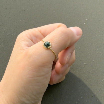 Hand wearing an African Turquoise Gemstone Fidget Ring on a dark surface