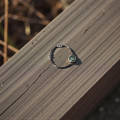 Silver ring with a green emerald stone on a wooden surface